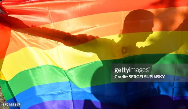 An activist's silhouette is seen through a rainbow flag during a Gay Parade in Kiev on May 25, 2013. Around a hundred gay rights activists marched in...