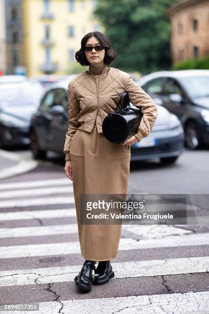 Proud Oranicha Krinchai is seen wearing black sunglasses, a beige bomber, a beige long skirt black boots, a beige turtle-neck sweater and a round...