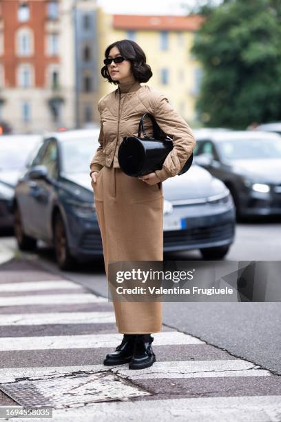 Proud Oranicha Krinchai is seen wearing black sunglasses, a beige bomber, a beige long skirt black boots, a beige turtle-neck sweater and a round...