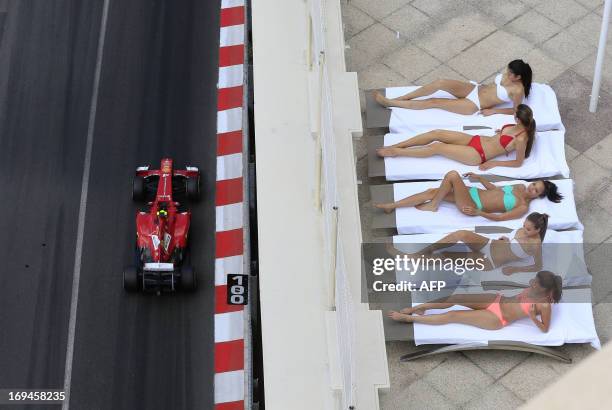 Women sunbath as Ferrari's Brazilian driver Felipe Massa drives past during the third practice session at the Circuit de Monaco in Monte Carlo on May...