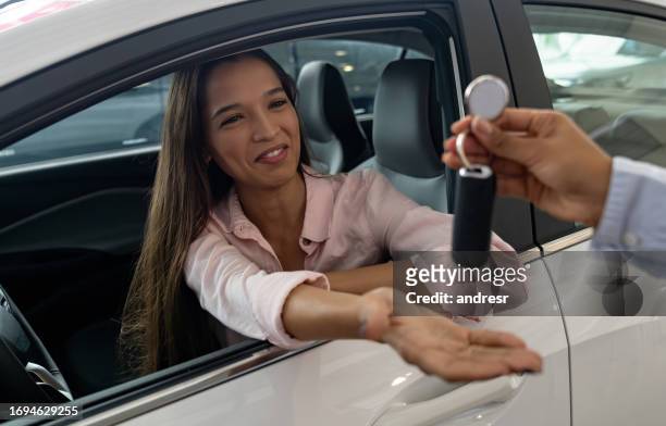 happy woman receiving the keys of her new car at the dealership - car dealership test drive stock pictures, royalty-free photos & images