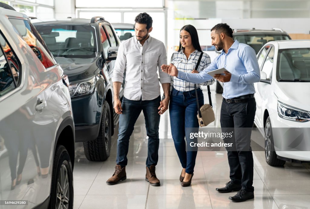 Vendedor na concessionária mostrando carro para casal
