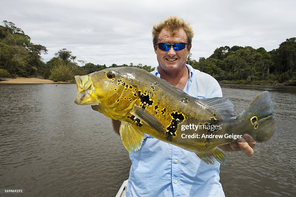 Man holding up Peacock Bass on Amazon River.