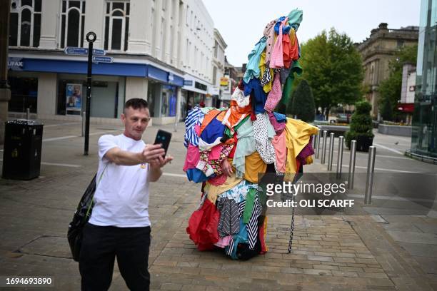 Pedestrian poses for a selfie photograph with artist Jeremy Hutchison, wearing his artwork entitled 'Dead White Man', created from secondhand...