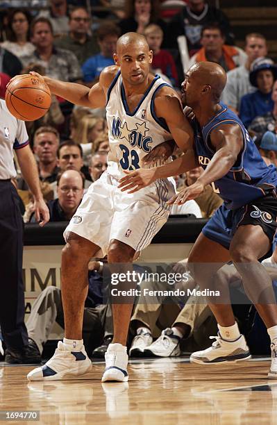 Grant Hill of the Orlando Magic drives against Bryon Russell of the Washington Wizards during the NBA game at TD Waterhouse Centre on December 6,...