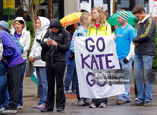Emily Hutchinson of Newton holds a sign reading, 'Go Kate Go!' as she waits for her sister, Kate, to cross the Boston Marathon finish line on...