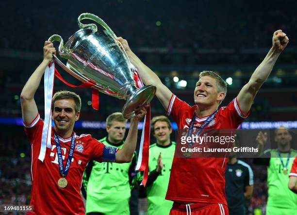 Philipp Lahm of Bayern Muenchen holds the trophy as he celebrates with team-mate Bastian Schweinsteiger after winning the UEFA Champions League final...