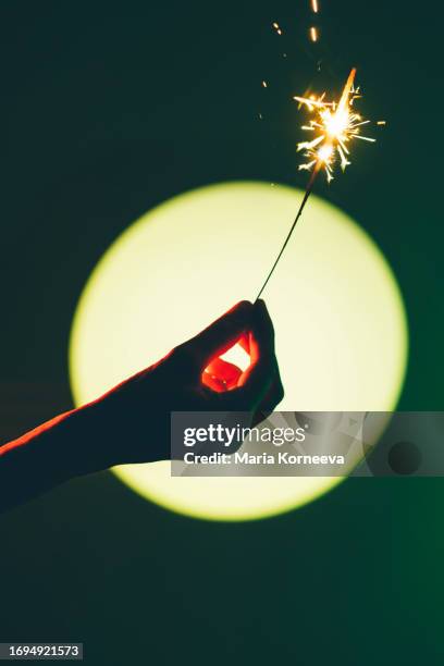 close-up hand holding of a sparkler on green background. - bengal fire stock pictures, royalty-free photos & images