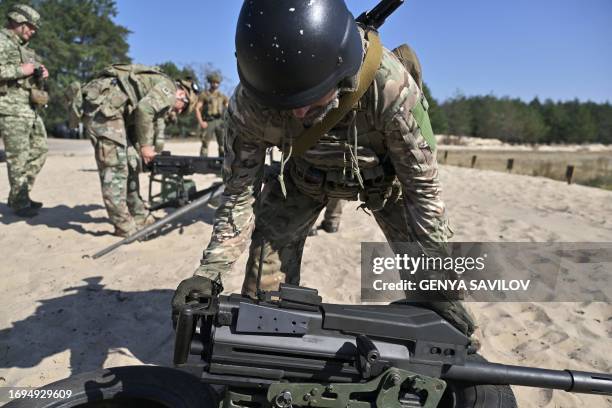 Ukrainian serviceman holds a US made MK19 automatic grenade launcher as other prepare to fire a Browning M2 machinegun during training exercise in...