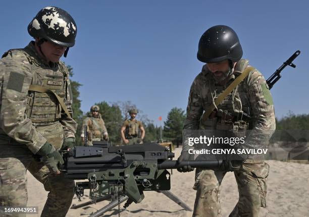 Ukrainian servicemen carry a US made MK19 automatic grenade launcher during training exercise in Kyiv region on September 27 amid the Russian...
