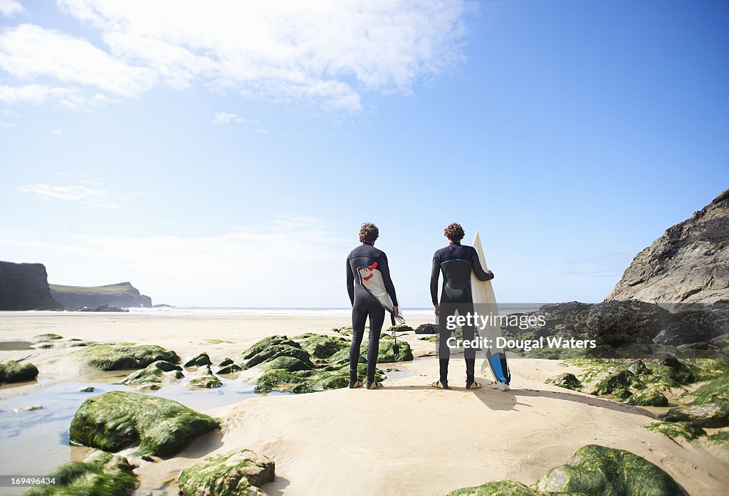 Two surfers looking towards sea.