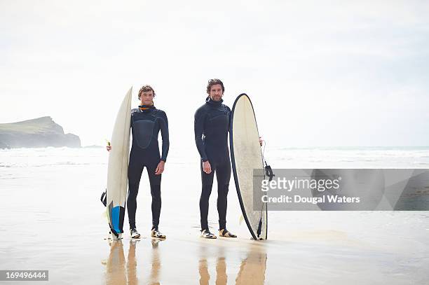 surfers standing at beach with surfboards. - wetsuit stock pictures, royalty-free photos & images