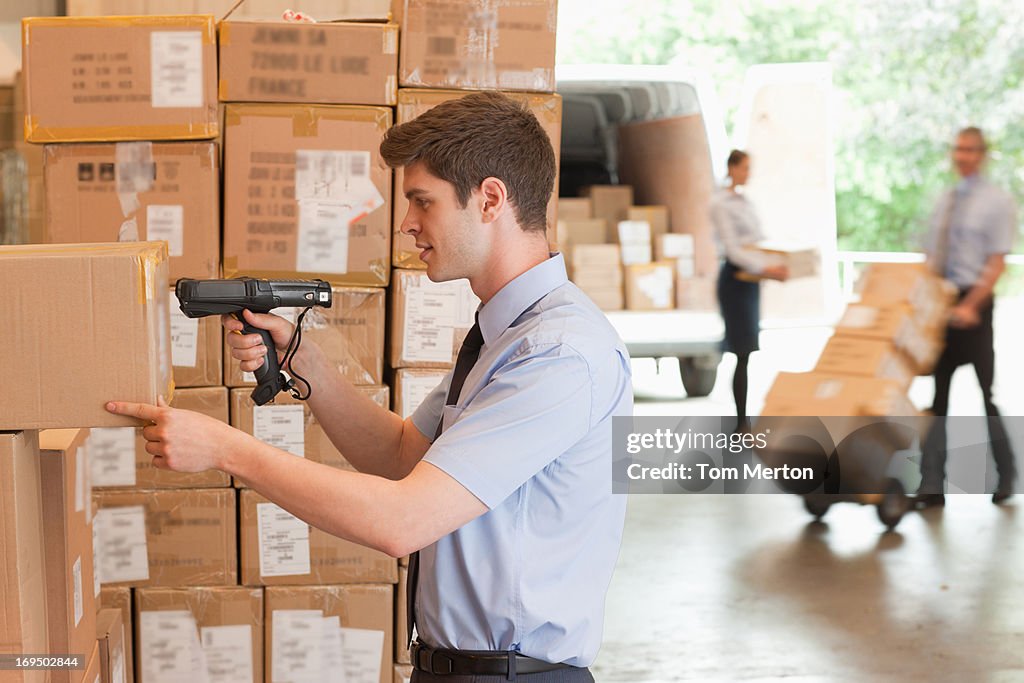 Businessman scanning shipping box in warehouse