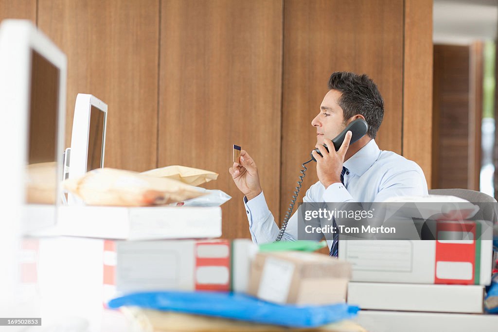 Empresário falando ao telefone atrás de pacotes