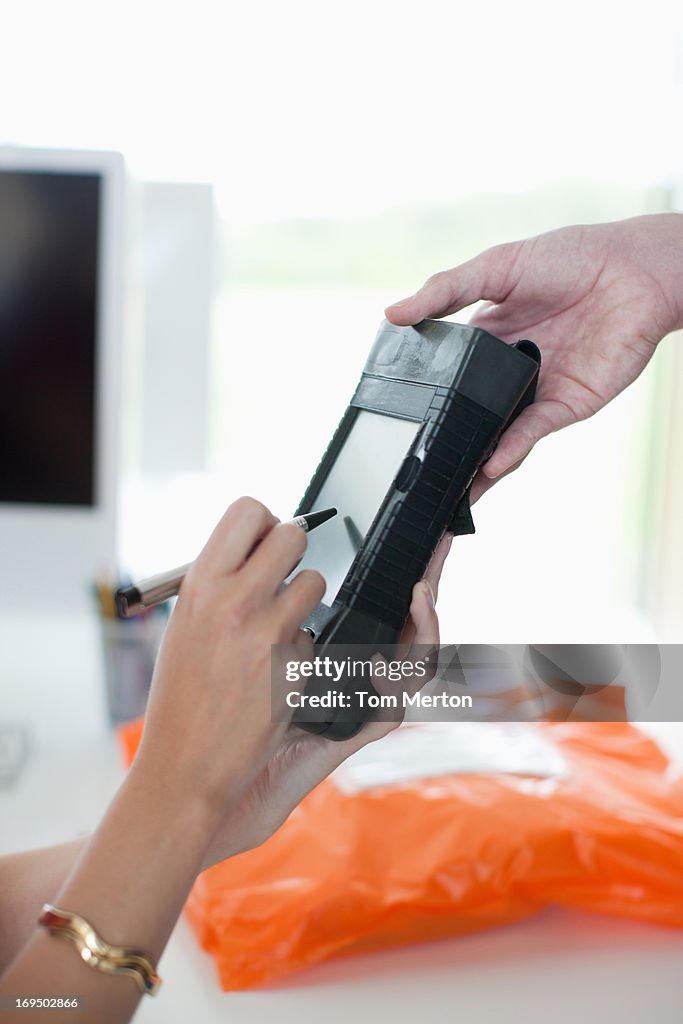 Woman writing signature on electronic device