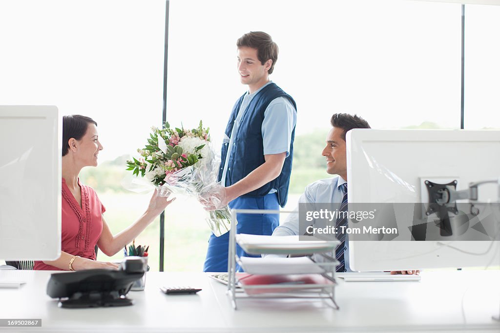 Deliveryman delivering flowers to businesswoman in office