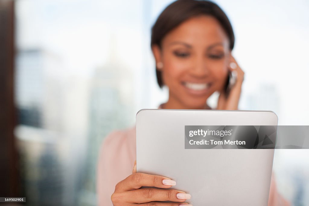 Businesswoman holding digital tablet y hablando por teléfono celular