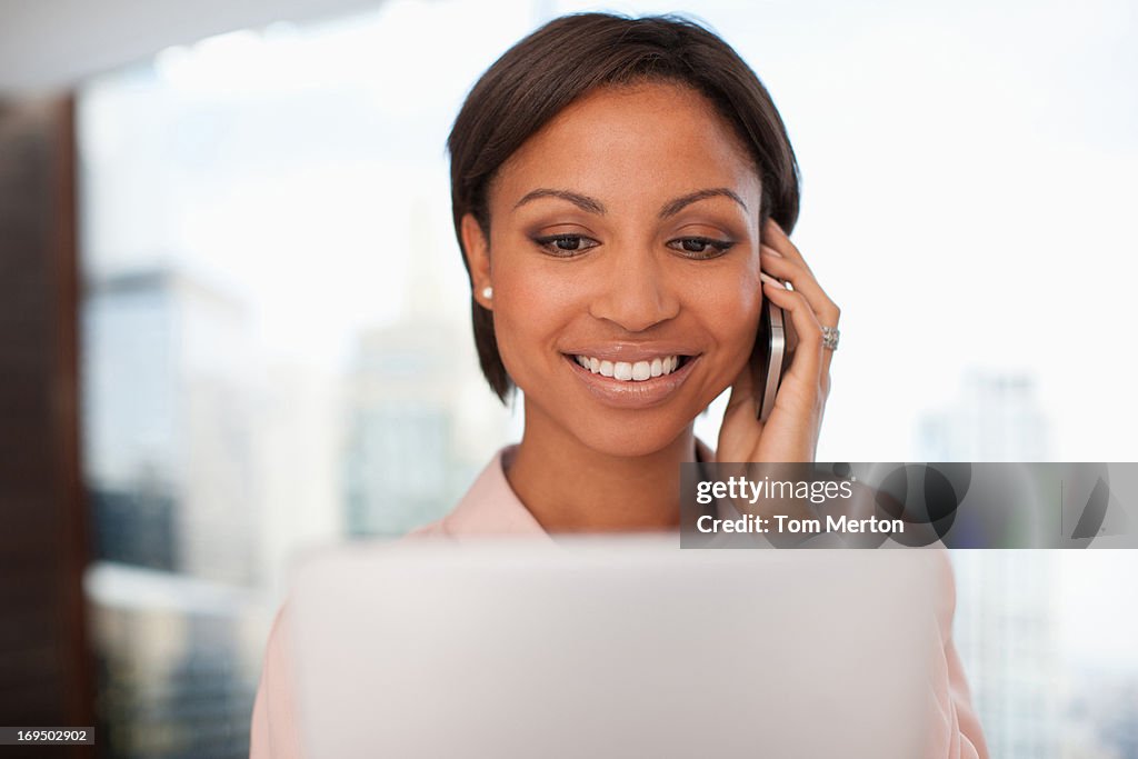 Businesswoman holding digital tablet and talking on cell phone