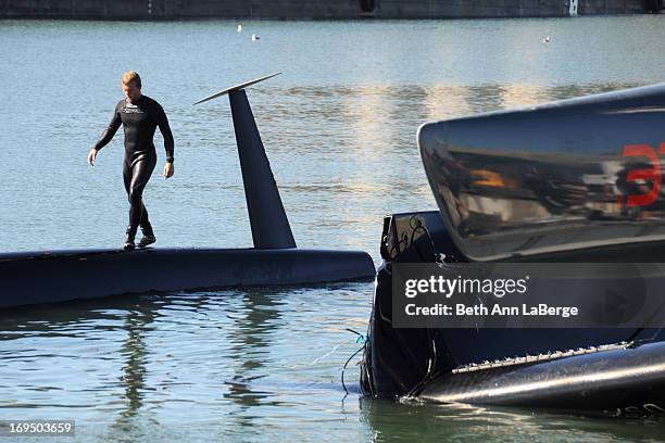 An Oracle team member walks along a capsized 72-foot Oracle Racing catamaran before it is hoisted onto Pier 80 on Wednesday Oct. 17, 2012 in San...