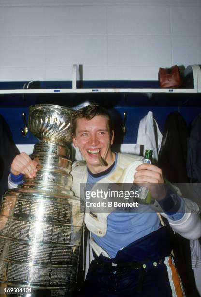 Jari Kurri of the Edmonton Oilers smokes a cigar and celebrates with the Stanley Cup Trophy in the locker room after the Oilers defeated the...