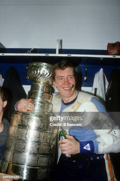Jari Kurri of the Edmonton Oilers smokes a cigar and celebrates with the Stanley Cup Trophy in the locker room after the Oilers defeated the...
