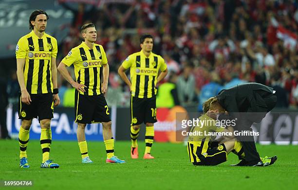 Neven Subotic, Lukasz Piszczek and Nuri Sahin of Borussia Dortmund look on as Marco Reus is consoled by Head Coach Jurgen Klopp of Borussia Dortmund...
