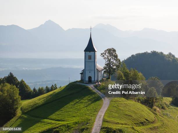 aerial perspective, sunrise over st. primoz church in jamnik on lush slovenian hill, kranj, gorenjska landmark photography - kranj - fotografias e filmes do acervo