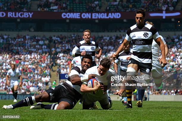 Freddie Burns of England crashes through the tackle from Takudzwa Ngwenya of The Barbarians to score the opening try during the rugby union...