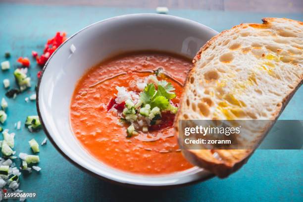 bowl of fresh tomato soup with onion and cucumber chops on top, served with bread slice - tomato soup stock pictures, royalty-free photos & images