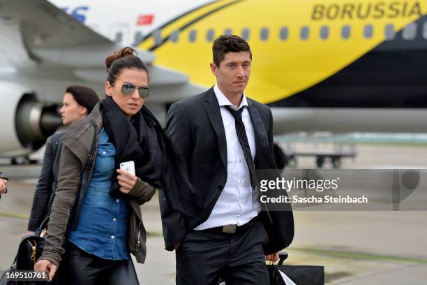 Robert Lewandowski and his fiance Anna Stachurska walk across the tarmac as the Borussia Dortmund return to Dortmund Airport after UEFA Champions...