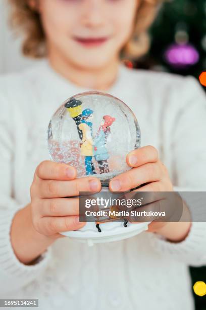 close-up girl standing next to christmas tree and playing with snow globe - funny snow globe - fotografias e filmes do acervo