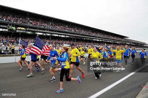 Runners who participated in the 2013 Boston Marathon run down pit road during the IZOD IndyCar Series 97th running of the Indianpolis 500 mile race...