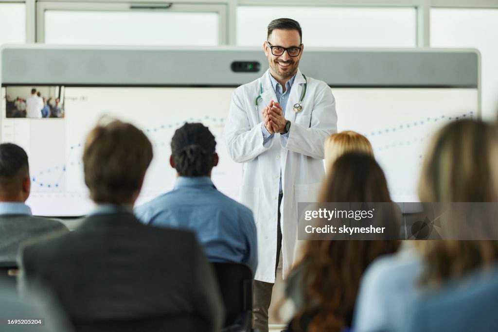 Happy male doctor leading a presentation in board room.