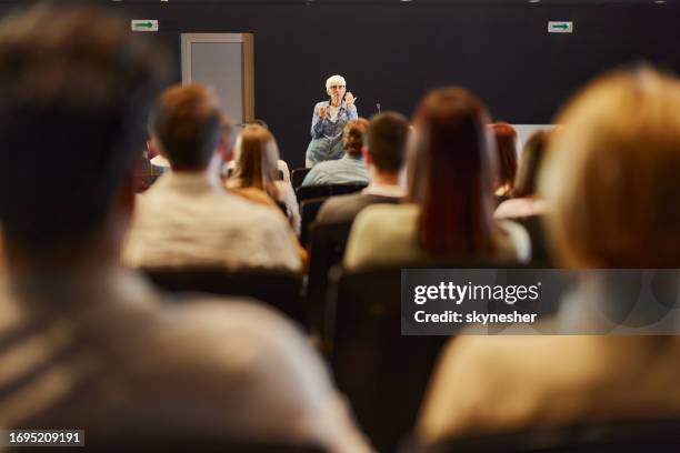 senior public speaker talking on a conference at convention center. - conference speaker stock pictures, royalty-free photos & images
