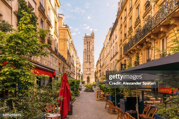 street with cafes and saint-jacques tower in paris, france - quartier du marais photos et images de collection