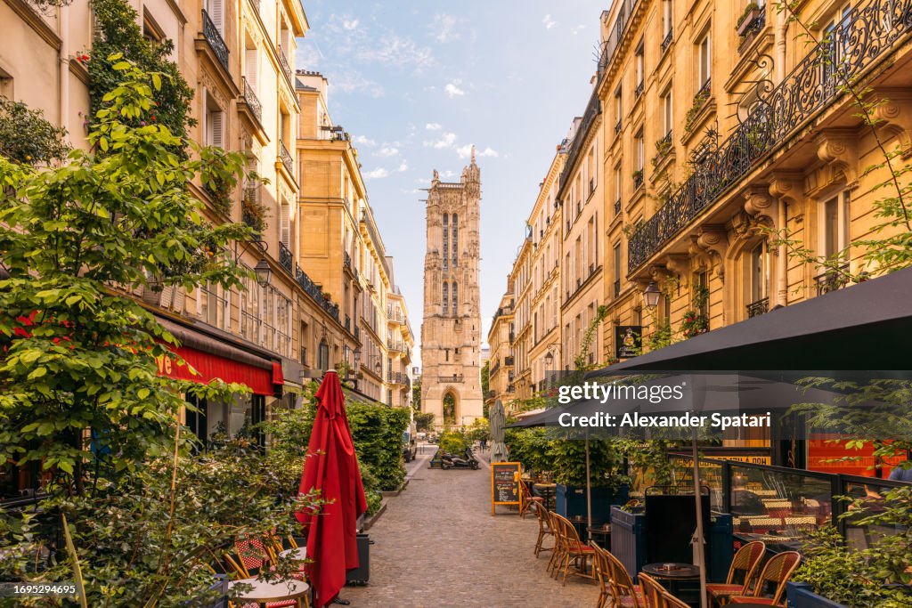 Street with cafes and Saint-Jacques Tower in Paris, France