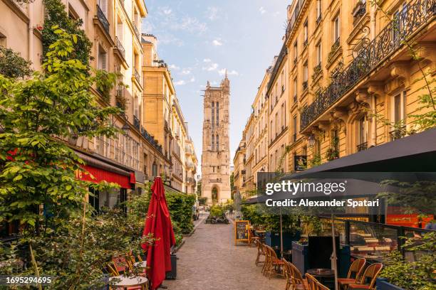 street with cafes and saint-jacques tower in paris, france - the marais stock pictures, royalty-free photos & images