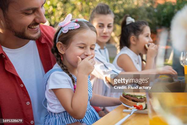 caucasian girl eating an burger, during family barbecue party - mother daughter brunch bildbanksfoton och bilder