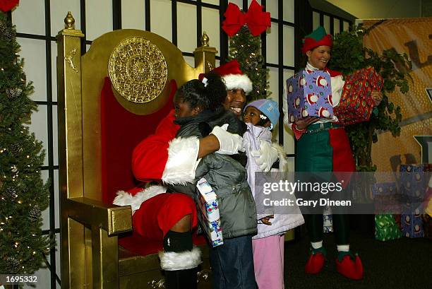 Milwaukee Bucks center Ervin Johnson gives out hugs and Christmas presents to local children as Terri Wilson, wife of Bucks strength and conditioning...