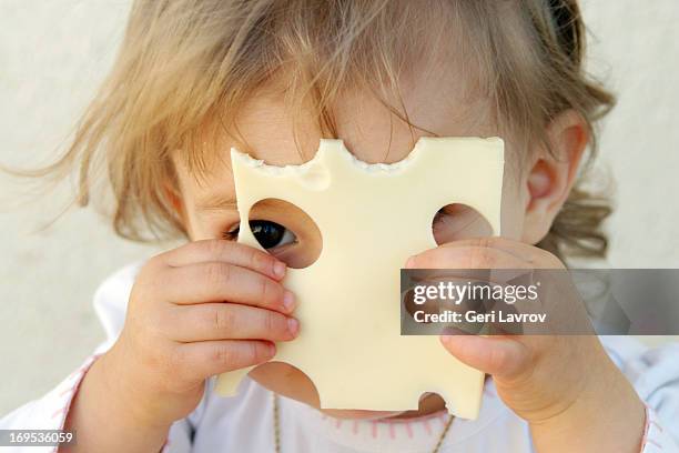 young girl holding a slice of cheese over her face - cheese slice foto e immagini stock