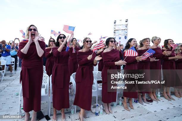 Wives and partners of Team United States members wave flags before the Opening Ceremony of the Ryder Cup at Marco Simone Golf & Country Club on...