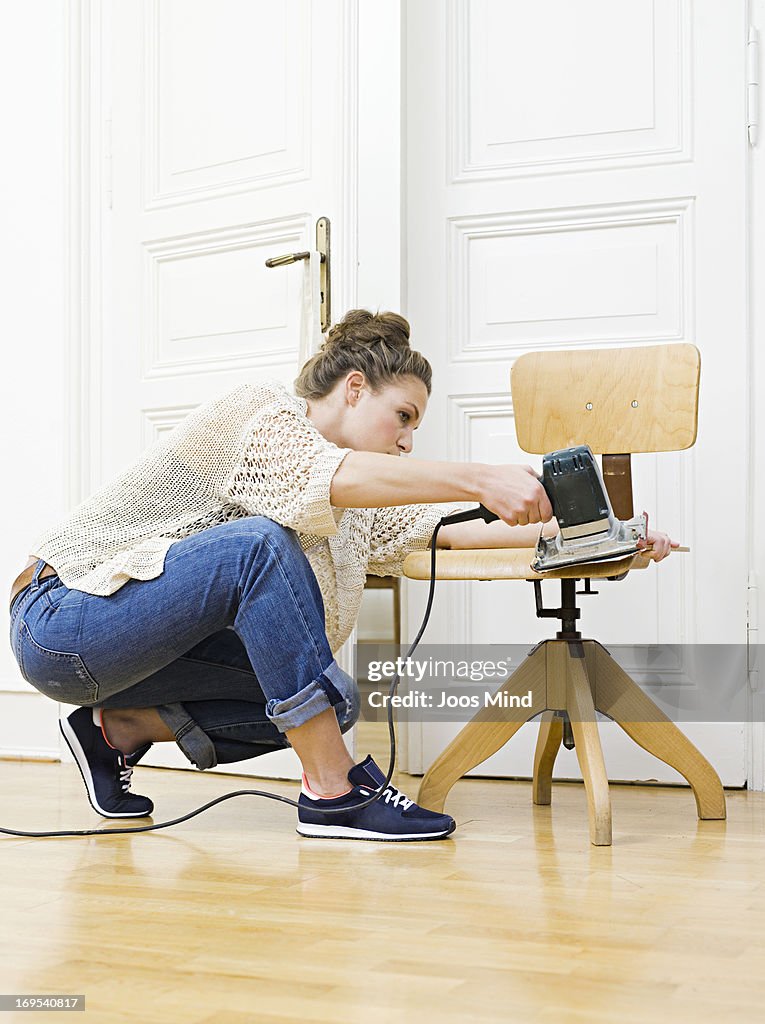 Young woman sanding chair