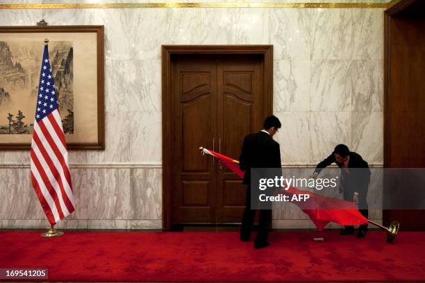 Workers iron a Chinese national flag after a US national flag is placed in front of a Chinese traditional painting before a meeting between US...