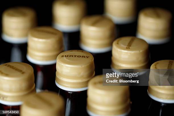 The Suntory Holdings Ltd. Logo is displayed on bottle caps for Suntory Beverage & Food Ltd.'s Kuro Oolong tea in this arranged photograph taken in...