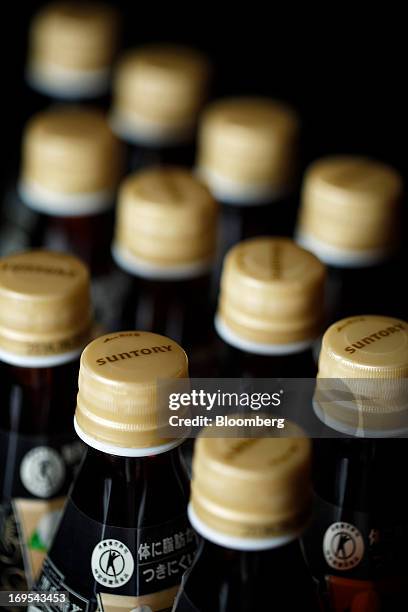 The Suntory Holdings Ltd. Logo is displayed on bottle caps for Suntory Beverage & Food Ltd.'s Kuro Oolong tea in this arranged photograph taken in...