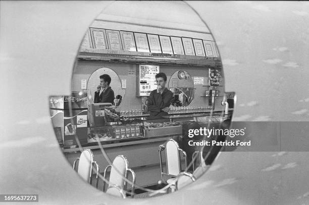 Man deep in thought viewed through a round shape in a window at a cafe and ice cream parlour, Broadstairs, Kent, 1985.