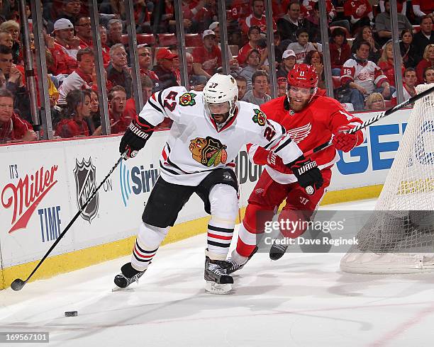 Johnny Oduya of the Chicago Blackhawks skates with the puck as and Daniel Cleary of the Detroit Red Wings gives chase during Game Six of the Western...