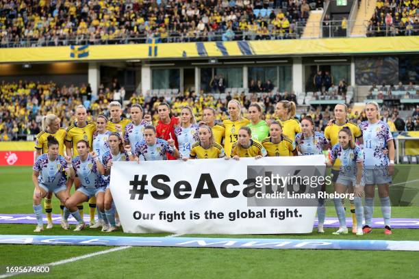 Players of Sweden and Spain hold a banner which reads 'SeAcabo, Our fight is the global fight.' in support of the Spain national women's team prior...