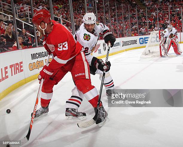 Corey Crawford of the Chicago Blackhawks watches teamate Michal Rozsival battle for the puck in the corner with Johan Franzen of the Detroit Red...
