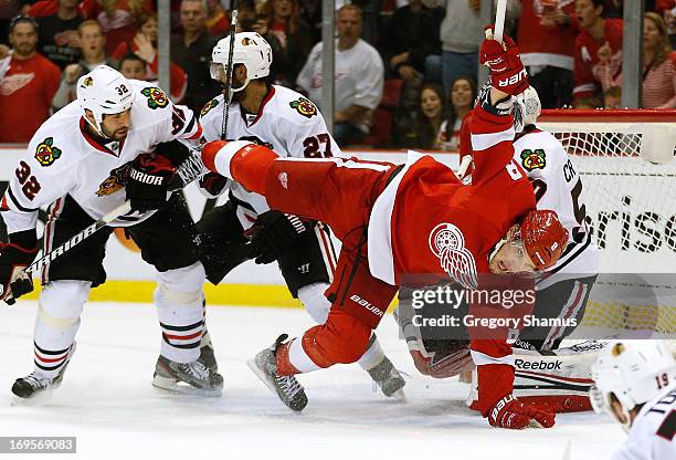 Justin Abdelkader of the Detroit Red Wings tries to stay on his feet between Michal Rozsival and Corey Crawford of the Chicago Blackhawks during the...